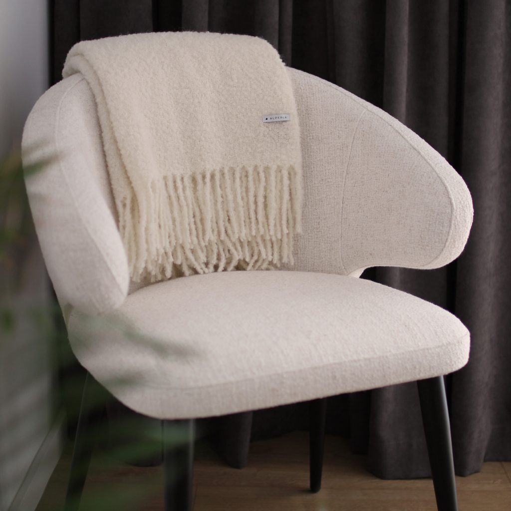 Biały koc z alpaki Alpaca Boucle na krześle